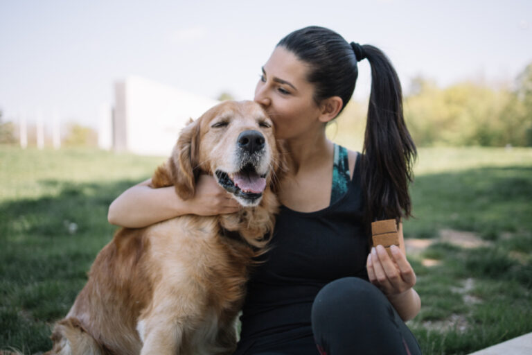 Woman hiking with dog giving supplement bar